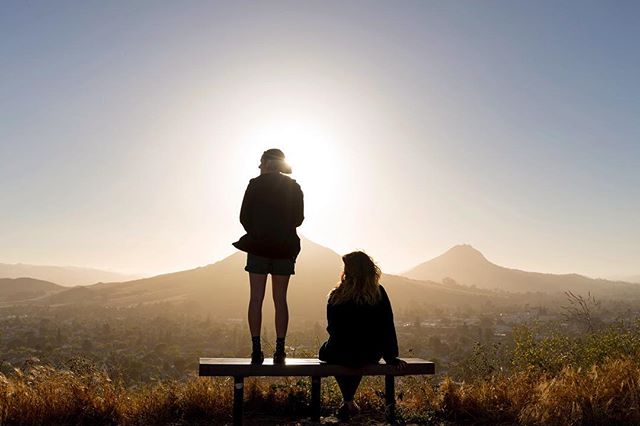 A photo of two hikers on top of Terrace Hill watching the sunset in SLO.,