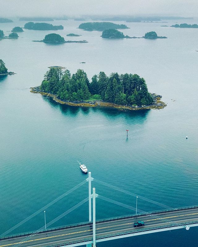 Photo from up above a bridge, with a boat and island in the water in the background.