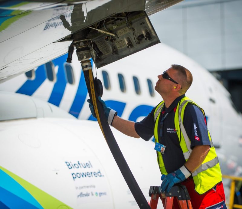 A photo of a male Swissport employee fueling an Alaska Airlines jet with biofuel.