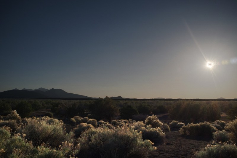 A photo looking out over the Arizona dessert with a partial solar eclipse shining in the sky.
