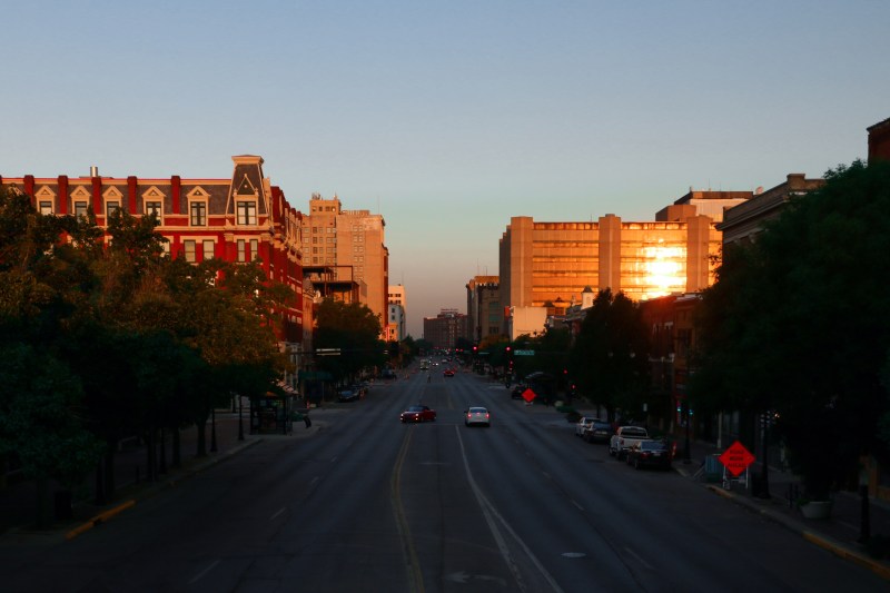 Photo of a Kansas sunset overlooking a busy highway with the sun reflecting off the buildings in the distance