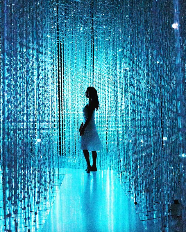 This is a photo of a girl standing in the middle of strings of blue LED lights.