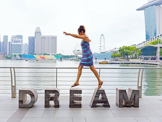 This is a photo of a girl standing on top of stone letters that spell the word DREAM.